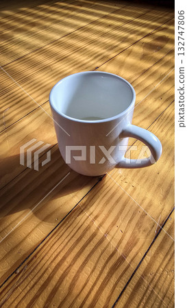 White Ceramic Coffee Mug Bathed in Morning Sunlight Across Warm Wooden Table Still Life Scene White Ceramic Coffee Mug Bathed in Morning Sunlight Across Warm Wooden Table Still Life Scene 132747806