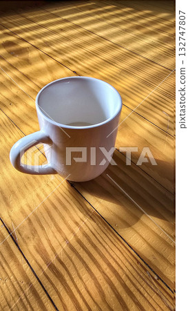 White Ceramic Coffee Mug Bathed in Morning Sunlight Across Warm Wooden Table Still Life Scene White Ceramic Coffee Mug Bathed in Morning Sunlight Across Warm Wooden Table Still Life Scene 132747807