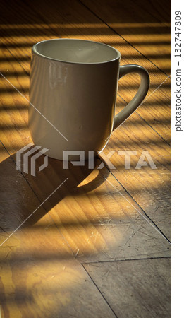 White Ceramic Coffee Mug Bathed in Morning Sunlight Across Warm Wooden Table Still Life Scene 132747809