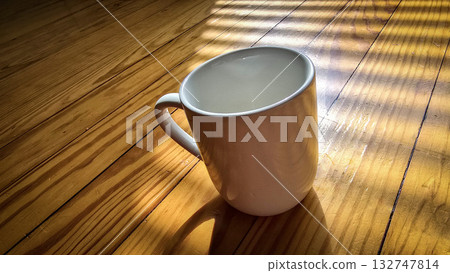 White Ceramic Coffee Mug Bathed in Morning Sunlight Across Warm Wooden Table Still Life Scene White Ceramic Coffee Mug Bathed in Morning Sunlight Across Warm Wooden Table Still Life Scene 132747814