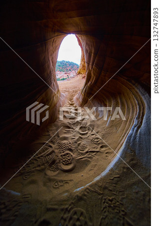 Sandstone Cave Tunnel with Hiker Footprints and Sunlit Utah Desert Entrance Sandstone Cave Tunnel with Hiker Footprints and Sunlit Utah Desert Entrance 132747893