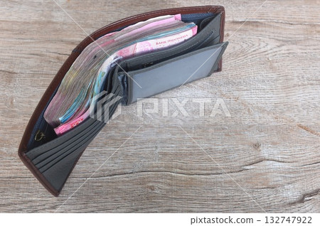 indonesia rupiah banknote in brown wallet on wooden table texture and background indonesia rupiah banknote in brown wallet on wooden table texture and background 132747922