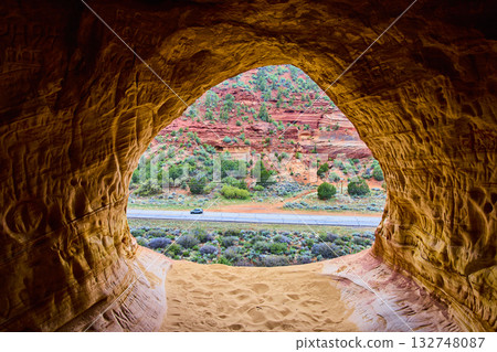 Sandstone Cave Window Over Red Rocks and Desert Road Utah Adventure Scene Sandstone Cave Window Over Red Rocks and Desert Road Utah Adventure Scene 132748087