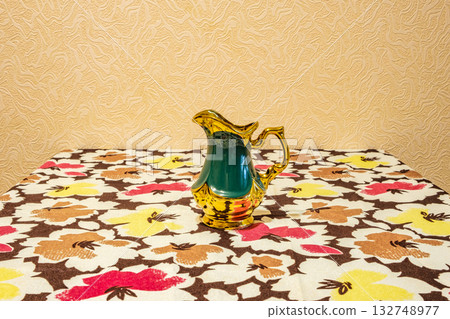 green and gold jug on table with tablecloth 132748977