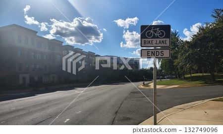 An empty residential road with a right-hand fork and a sign indicating a bike lane and end of the road, a deserted city highway with a right-hand turn and a bike path 132749096