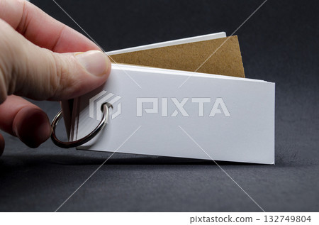 Hand holding white banner shape notepad with customizable space for text on black cover background. Hand holding white banner shape notepad with customizable space for text on black cover background. 132749804