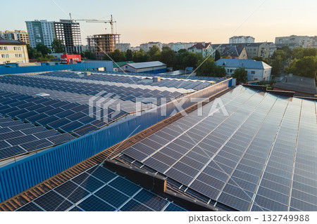 Aerial view of blue photovoltaic solar panels mounted on industrial building roof for producing green ecological electricity. Production of sustainable energy concept Aerial view of blue photovoltaic solar panels mounted on industrial building roof for producing green ecological electricity. Production of sustainable energy concept 132749988