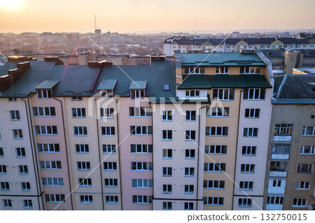 Aerial view of attic annex room exterior with plastic windows, roof and walls covered with green metal siding planks, new gutter system on top of high multi-storey apartment building. Aerial view of attic annex room exterior with plastic windows, roof and walls covered with green metal siding planks, new gutter system on top of high multi-storey apartment building. 132750015
