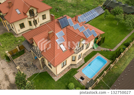 Aerial view of a new autonomous house with solar panels and water heating radiators on the roof and green yard with blue swimming pool. Aerial view of a new autonomous house with solar panels and water heating radiators on the roof and green yard with blue swimming pool. 132750027