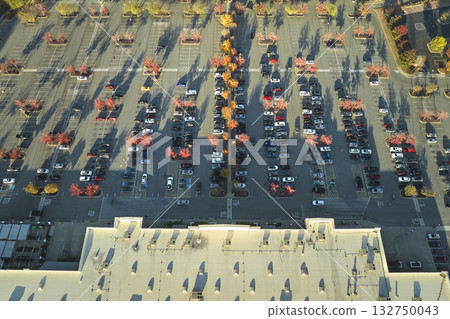 Aerial view grocery shopping mall and many colorful cars parked on parking lot with lines and markings for parking places and directions. Place for vehicles in front of a strip mall plaza Aerial view grocery shopping mall and many colorful cars parked on parking lot with lines and markings for parking places and directions. Place for vehicles in front of a strip mall plaza 132750043