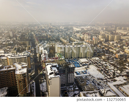 Aerial black and white winter top view of modern city center with tall buildings and parked cars on snowy streets. Aerial black and white winter top view of modern city center with tall buildings and parked cars on snowy streets. 132750065