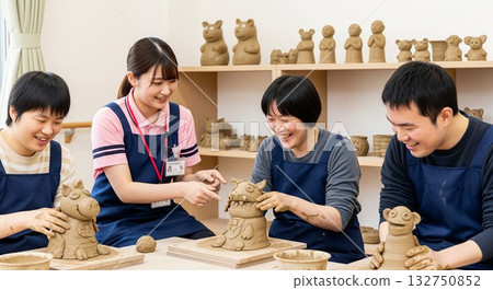 Smiling disabled people enjoying clay crafts and a female support worker gently supporting them (creative activities) Pottery class Art Artistic activities Smiling disabled people enjoying clay crafts and a female support worker gently supporting them (creative activities) Pottery class Art Artistic activities 132750852