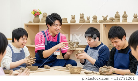 一位男性社工（福利/工作坊）面帶微笑地與使用者互動，同時進行陶藝創作。陶藝/陶藝，創意娛樂 132751201