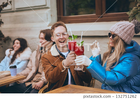 Friends toasting with winter cocktails outdoors in cozy city cafe Friends toasting with winter cocktails outdoors in cozy city cafe 132751262