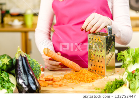 Woman grating carrot on metal grater 132752447