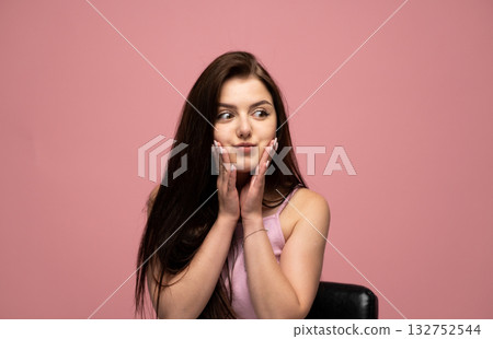 Playful brunette woman with long hair holding cheeks and making funny surprised face 132752544