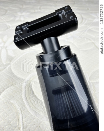 A portable cordless vacuum cleaner placed on a clean white mattress. Concept of home cleaning, furniture care, and household chores. Minimalistic composition symbolizing cleanliness and order 132752736