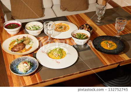 Enjoy a Gourmet Dining Event with a Variety of Delicious Dishes on a Beautiful Wooden Table 132752745