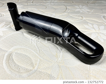 A portable cordless vacuum cleaner placed on a clean white mattress. Concept of home cleaning, furniture care, and household chores. Minimalistic composition symbolizing cleanliness and order 132752772
