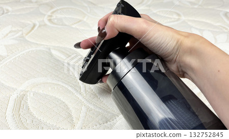 Woman hand attaching a nozzle to a portable cordless vacuum cleaner against a white mattress. Home cleaning preparation, household routine, and furniture care concept. Cleanliness and comfort Woman hand attaching a nozzle to a portable cordless vacuum cleaner against a white mattress. Home cleaning preparation, household routine, and furniture care concept. Cleanliness and comfort 132752845