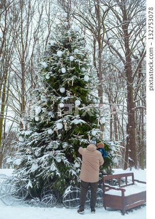 Decorating a Christmas tree in a snowy forest Decorating a Christmas tree in a snowy forest 132753078