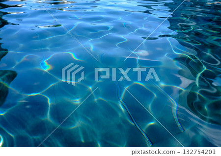Close-up of the water of a swimming pool with the sunlight reflection. The scene of the swimming pool in the sunny day. Relaxation and holiday concept. Close-up of the water of a swimming pool with the sunlight reflection. The scene of the swimming pool in the sunny day. Relaxation and holiday concept. 132754201
