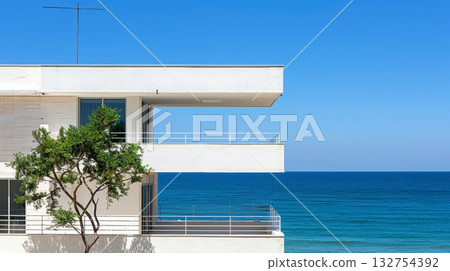 Modern White Villa with Balconies Overlooking a Tranquil Clear Blue Sea on a Sunny Summer Day 132754392