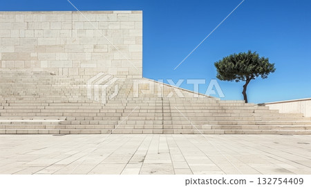 Minimalist Architecture With Stone Stairs, Blank Wall, And Lone Tree Against Blue Sky 132754409