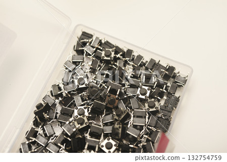 Black electronic buttons in a plastic container. Electronic elements. Black electronic buttons in a plastic container. Electronic elements. 132754759