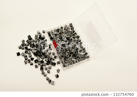 Black electronic buttons in a plastic container. Electronic elements. 132754760