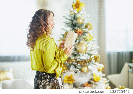 Woman Smiling with a Book by the Festive Christmas Tree Woman Smiling with a Book by the Festive Christmas Tree 132755441