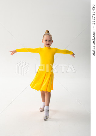 Smiling child in bright yellow practicing choreography with hearing device. Confidence, concentration, and harmony of movement despite deafness, showing inclusion and technological progress in Smiling child in bright yellow practicing choreography with hearing device. Confidence, concentration, and harmony of movement despite deafness, showing inclusion and technological progress in 132755456
