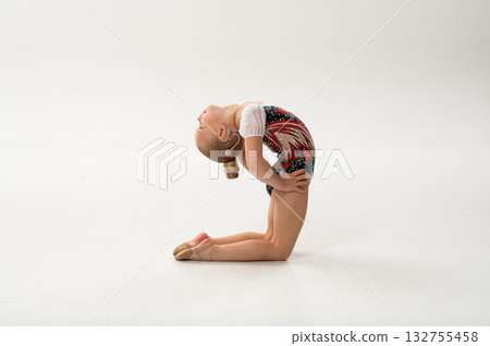 Young gymnast with cochlear implant performing elegant back arch, inclusion concept. Copy space. Expression of strength, inclusion, and body awareness through hearing restoration and sport. 132755458