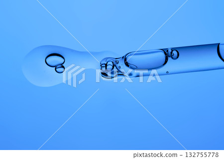 Dropper dropper with cosmetic serum on a blue background. 132755778