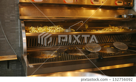 Commercial kitchen fryer with freshly cooked french fries and frying baskets Commercial kitchen fryer with freshly cooked french fries and frying baskets 132756092