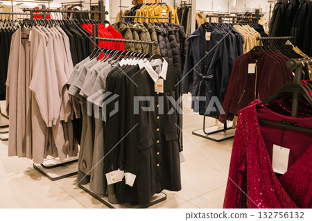 Fashion store interior displaying a variety of stylish coats and dresses on racks. Shopping Cart Day Fashion store interior displaying a variety of stylish coats and dresses on racks. Shopping Cart Day 132756132