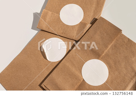 Brown paper bags with blank round white stickers on minimalist background 132756148