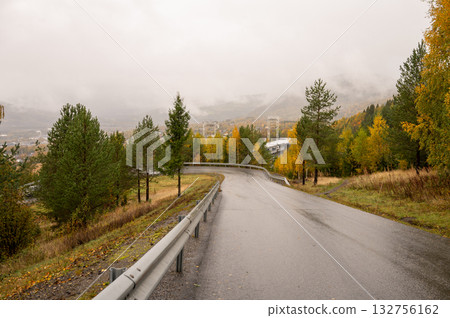 Scenic autumn road through misty forested hillside landscape 132756162
