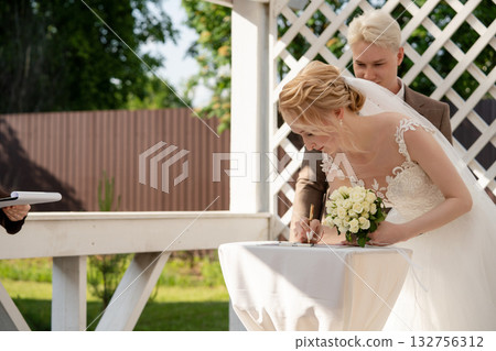 Couple signs marriage certificate in beautiful outdoor ceremony setting Couple signs marriage certificate in beautiful outdoor ceremony setting 132756312