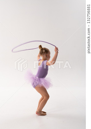 Little ballerina with cochlear implant holding jump rope in studio. Inclusive childhood, hearing technology, and confidence through rhythm, grace, and balance. 132756881