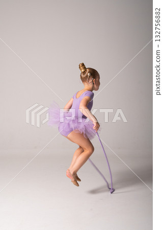 Little ballerina with cochlear implant holding jump rope in studio. Inclusive childhood, hearing technology, and confidence through rhythm, grace, and balance. 132756882