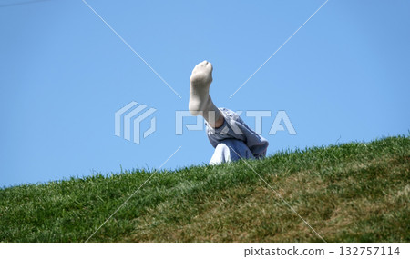 Legs clad in socks, one leg on top of the other, human resting pose on a hill Legs clad in socks, one leg on top of the other, human resting pose on a hill 132757114