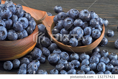 ripe juicy blueberries in a spoon on the table. close up ripe juicy blueberries in a spoon on the table. close up 132757421