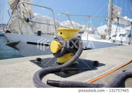 Yellow mooring bollard with rope on pier 132757465
