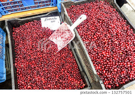 Red cranberries arranged for sale at an outdoor market. Text in Russian: cranberry Red cranberries arranged for sale at an outdoor market. Text in Russian: cranberry 132757501