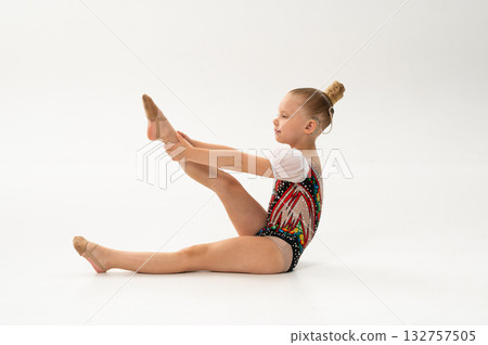 Girl gymnast with cochlear implant raising legs during exercise. Connection of art, sport, and hearing technology showing equality and perseverance. Girl gymnast with cochlear implant raising legs during exercise. Connection of art, sport, and hearing technology showing equality and perseverance. 132757505
