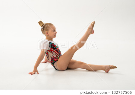 Girl gymnast with cochlear implant raising legs during exercise. Connection of art, sport, and hearing technology showing equality and perseverance. Girl gymnast with cochlear implant raising legs during exercise. Connection of art, sport, and hearing technology showing equality and perseverance. 132757506