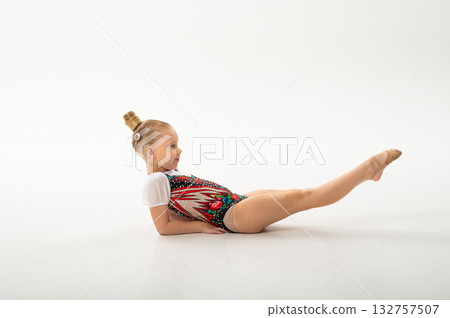 Girl gymnast with cochlear implant raising legs during exercise. Connection of art, sport, and hearing technology showing equality and perseverance. Girl gymnast with cochlear implant raising legs during exercise. Connection of art, sport, and hearing technology showing equality and perseverance. 132757507