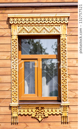 Facade of village house decorated with wooden carvings, platbands, wooden lace ornament 132757521