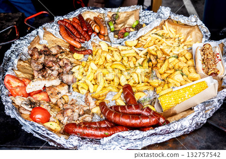 Frying pan with fried potatoes, sausages, meat, vegetables and pepper. Street food and outdoor cooking Frying pan with fried potatoes, sausages, meat, vegetables and pepper. Street food and outdoor cooking 132757542